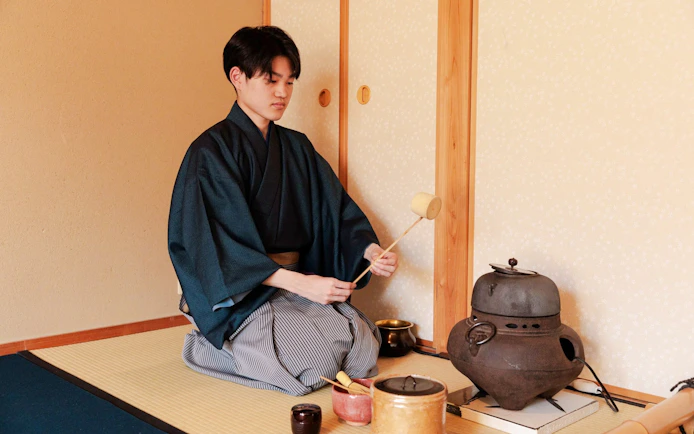 Person performing traditional tea ceremony in Japanese room.