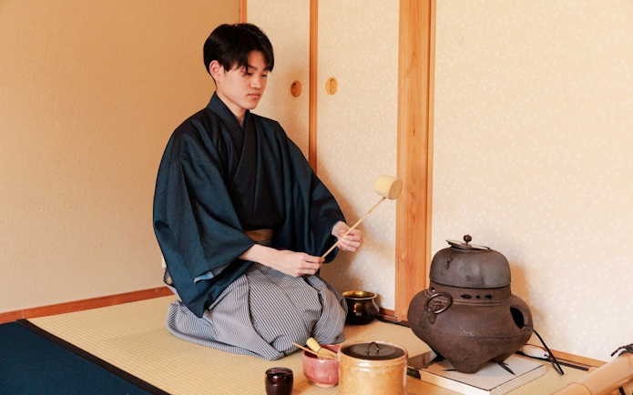 Person performing traditional tea ceremony in Japanese room.