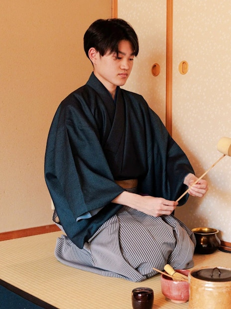 Person performing traditional tea ceremony in Japanese room.
