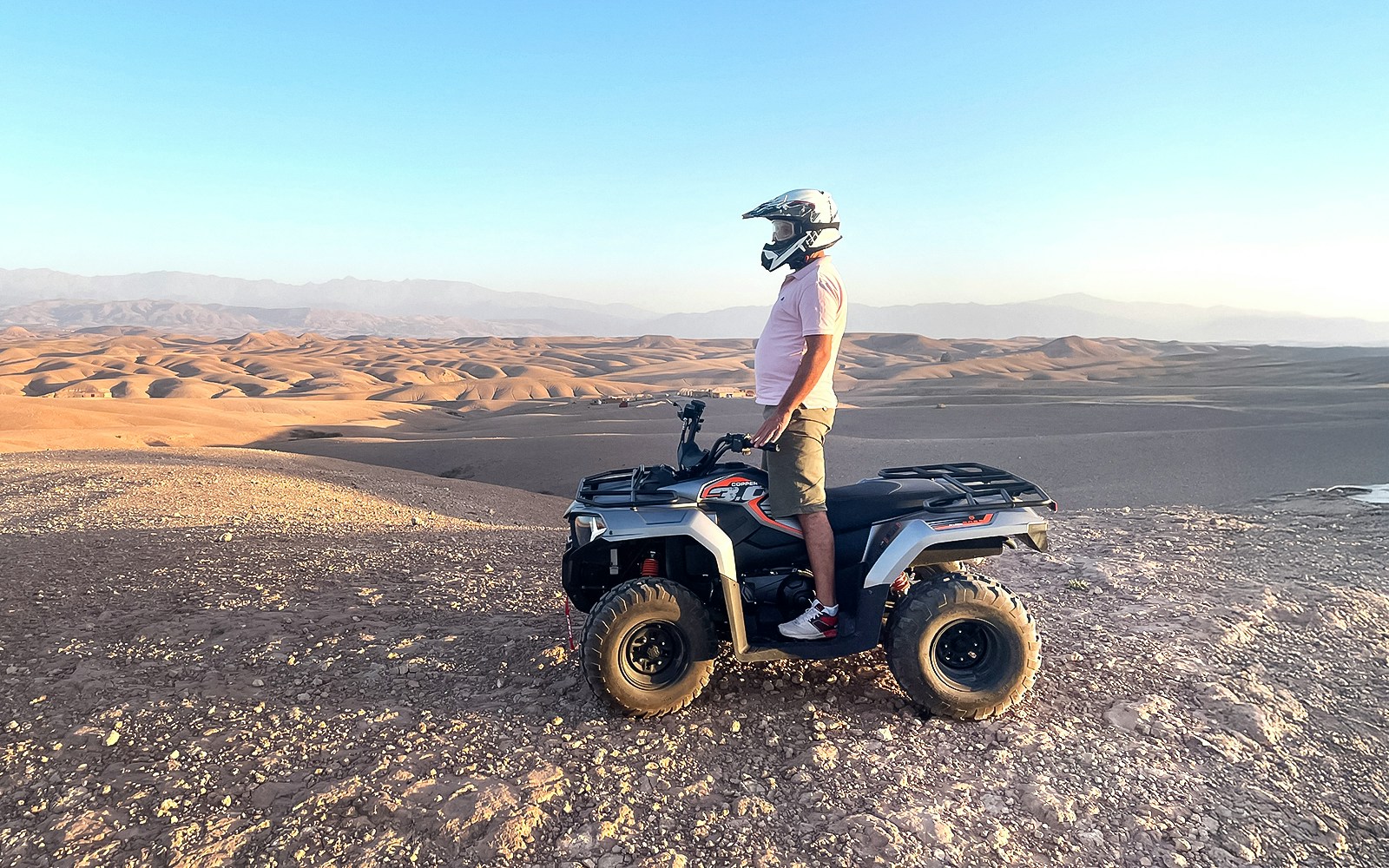 Person on quad bike overlooking Agafay Desert landscape during guided tour.