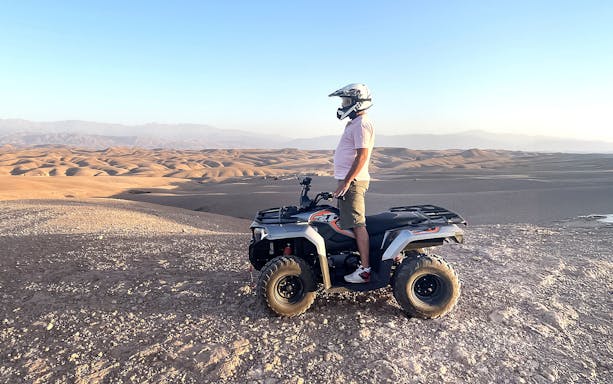 Person on quad bike overlooking Agafay Desert landscape during guided tour.