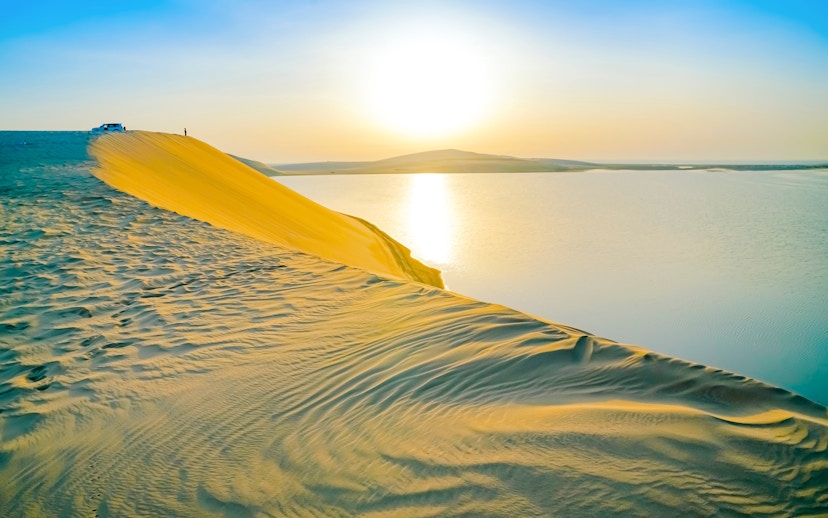 Sand dune overlooking the Inland Sea in Doha at sunset.