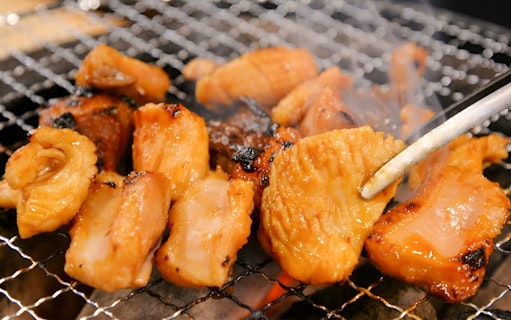 Grilled Wagyu beef pieces on a barbecue grill at Nikusen Tonya.