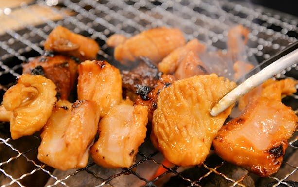 Grilled Wagyu beef pieces on a barbecue grill at Nikusen Tonya.