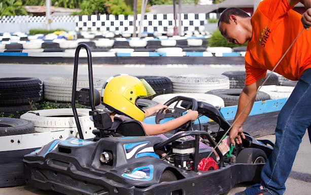 Child in go-kart with staff assistance at Bali Hai Pier Pattaya outdoor karting track.