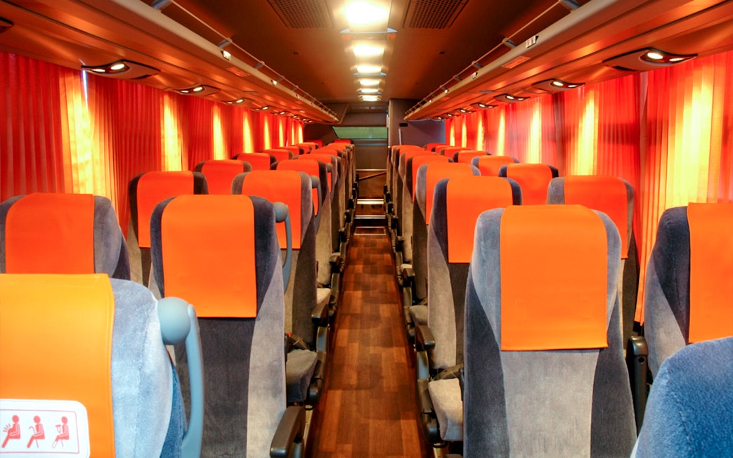 Interior of a limousine bus with orange seats, used for tourist transport in Tokyo.