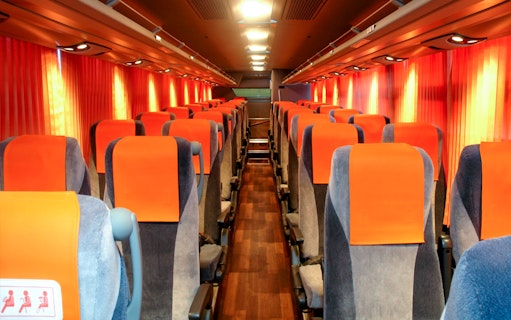 Interior of a limousine bus with orange seats, used for tourist transport in Tokyo.