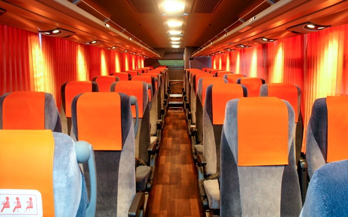 Interior of a limousine bus with orange seats, used for tourist transport in Tokyo.
