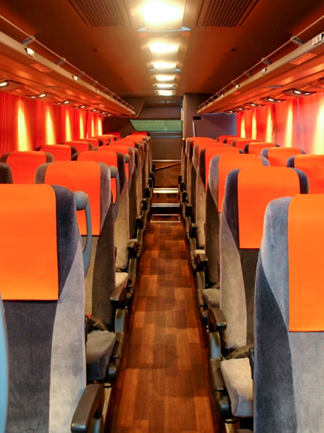 Interior of a limousine bus with orange seats, used for tourist transport in Tokyo.