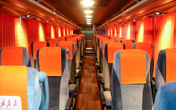 Interior of a limousine bus with orange seats, used for tourist transport in Tokyo.