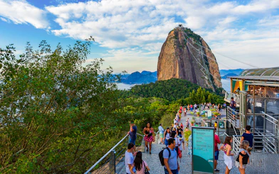 Visitors at Sugarloaf Mountain, Rio de Janeiro, with cable car and scenic views.