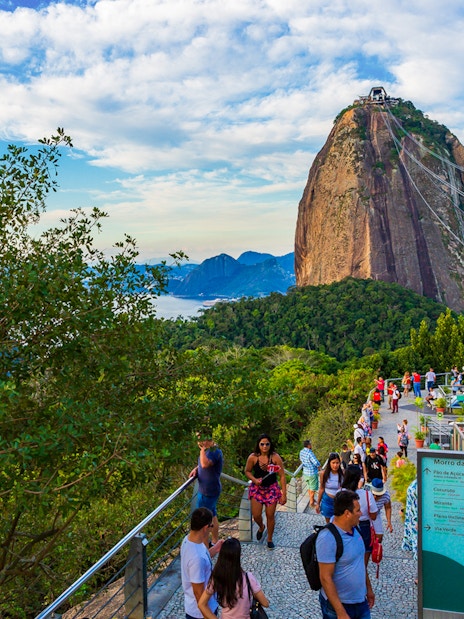 Visitors at Sugarloaf Mountain, Rio de Janeiro, with cable car and scenic views.