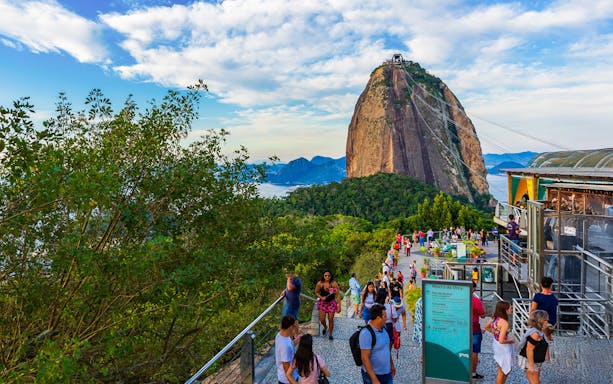 Visitors at Sugarloaf Mountain, Rio de Janeiro, with cable car and scenic views.