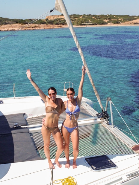Guests enjoying a catamaran ride near a scenic coastline.