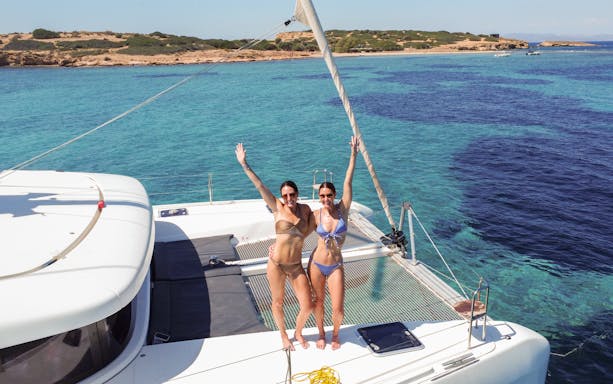 Guests enjoying a catamaran ride near a scenic coastline.