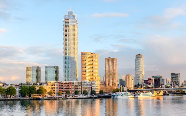 Rotterdam skyline with modern skyscrapers and boats on the harbor during a sightseeing cruise.