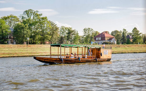 Private gondola on Krakow river cruise with passengers enjoying scenic views.