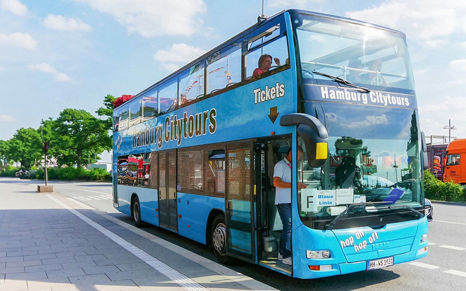 Hop-on hop-off sightseeing bus in Hamburg with city landmarks in the background.