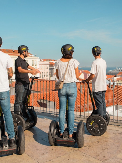 Tourists on Segways overlooking Alfama's rooftops in Lisbon during a guided tour.