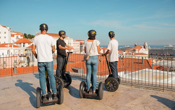 Tourists on Segways overlooking Alfama's rooftops in Lisbon during a guided tour.