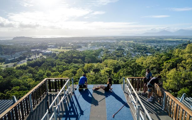 People preparing for Walk The Plank by AJ Hackett, overlooking lush landscape and distant mountains.