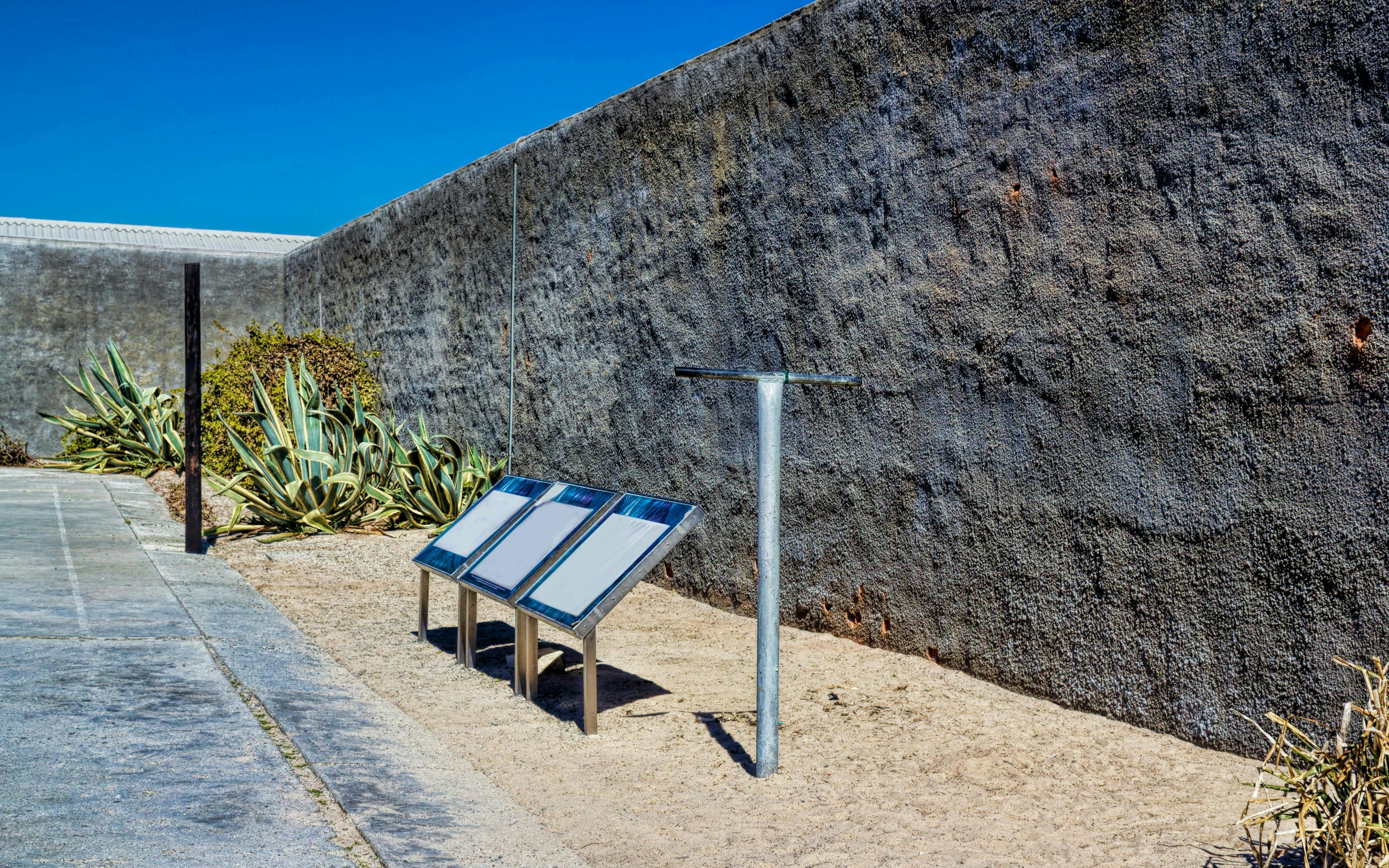 Robben Island Prison courtyard with informational plaques and stone wall.