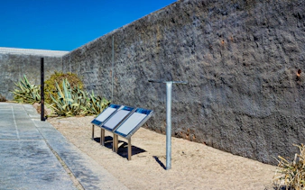 Robben Island Prison courtyard with informational plaques and stone wall.