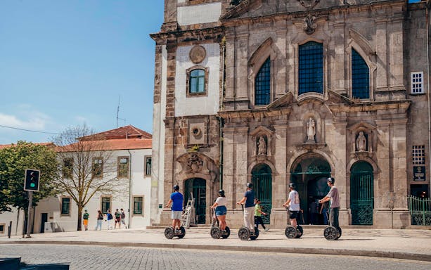 Tourists on Segways with guide in front of historic building in Porto.