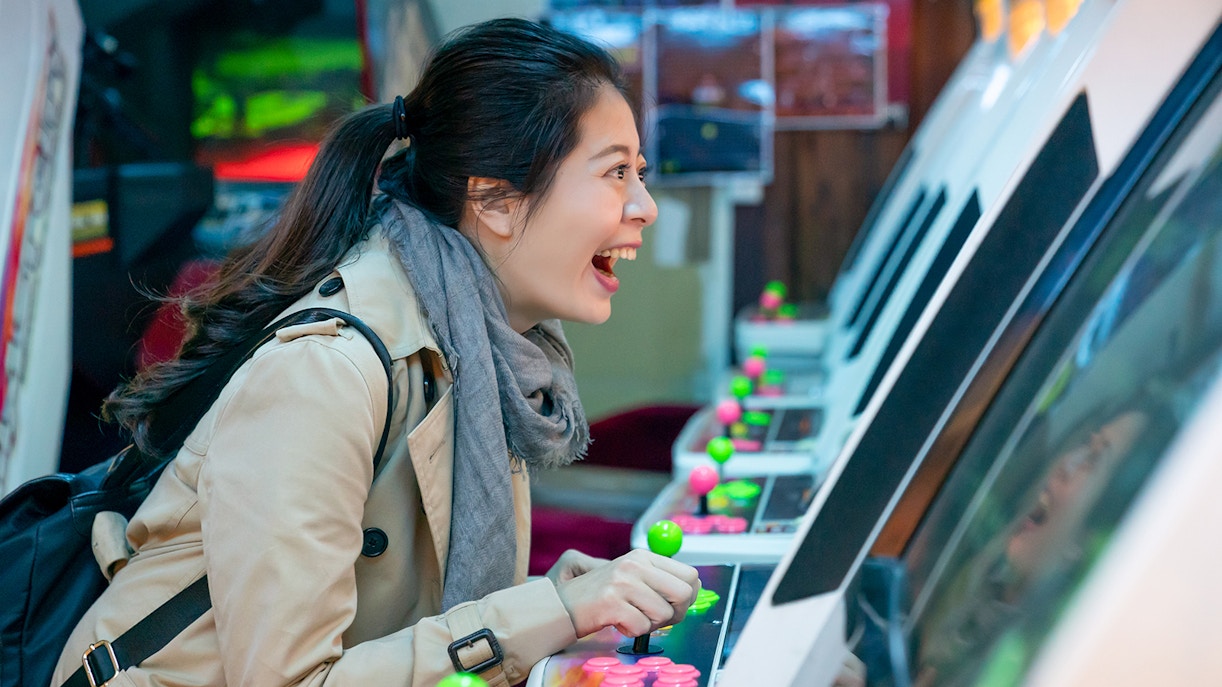 Person enjoying arcade game in Akihabara during retro gaming and anime walking tour.
