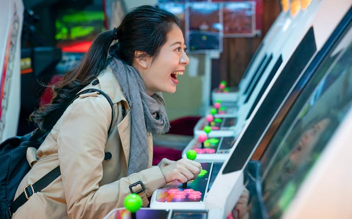 Person enjoying arcade game in Akihabara during retro gaming and anime walking tour.