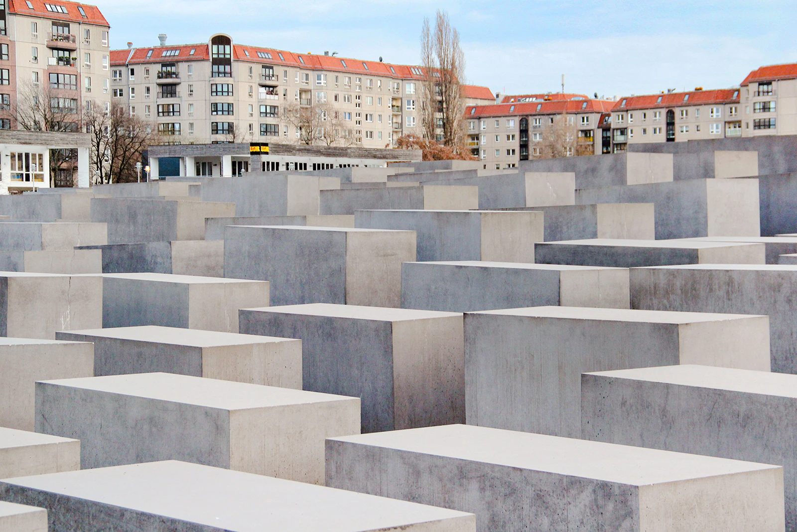 Holocaust Memorial in Berlin with concrete slabs and surrounding buildings.