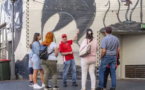 Tour group exploring street art in Perth laneway with guide.