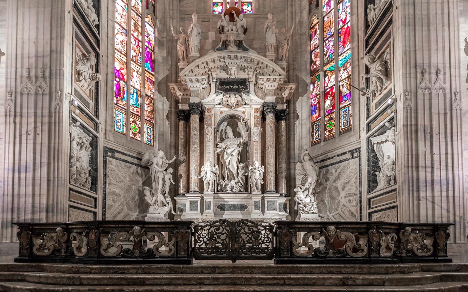 Duomo Cathedral Milan interior with ornate columns, detailed ceiling, and stained glass windows.