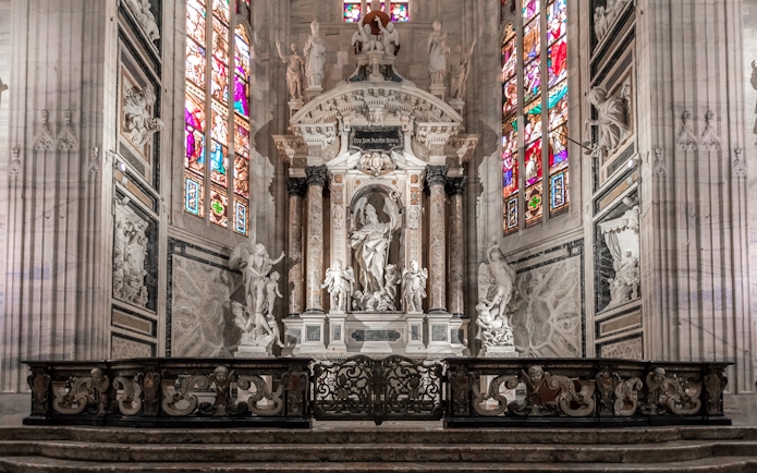 Duomo Cathedral Milan interior with ornate columns, detailed ceiling, and stained glass windows.