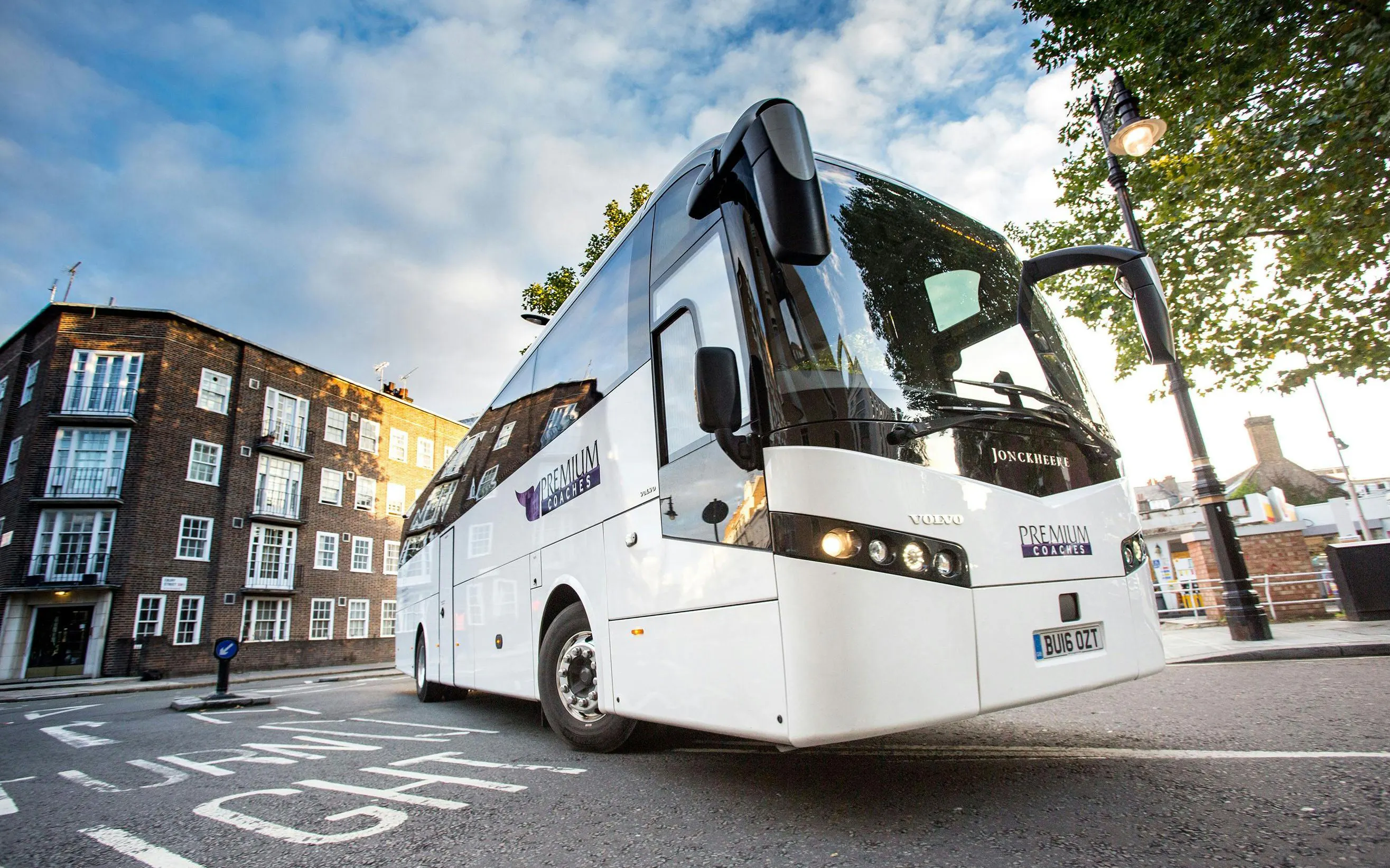 Tour bus parked on a city street, ready for passenger transfer.