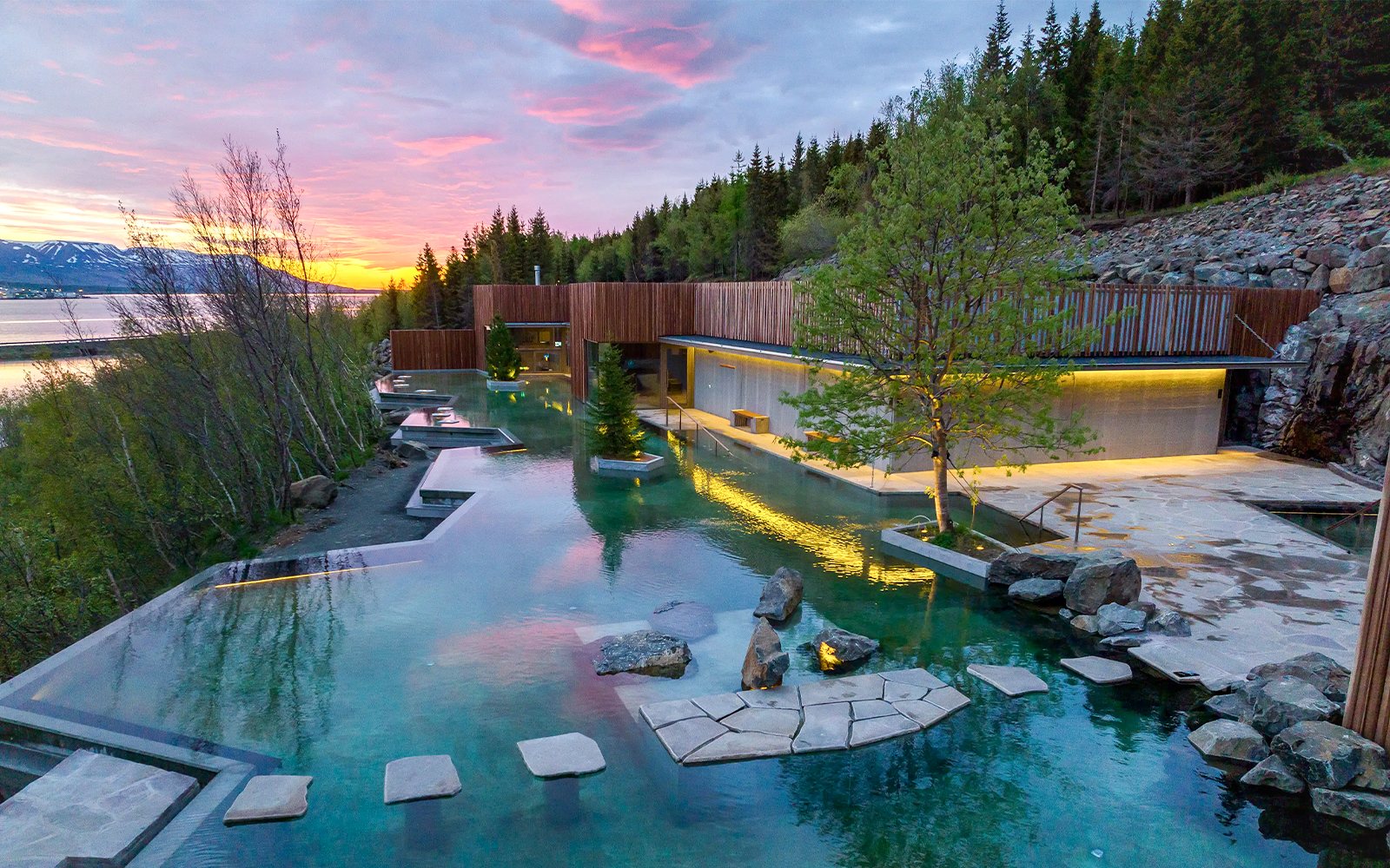 Forest lagoon with swimming pool and dim lighting at sunset in Akureyri.