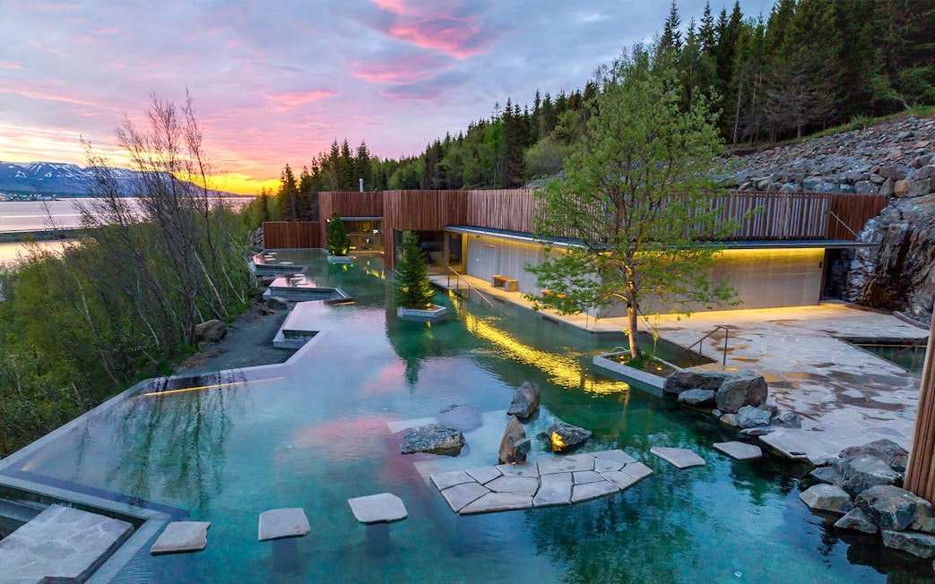 Forest lagoon with swimming pool and dim lighting at sunset in Akureyri.