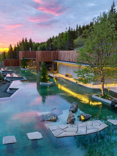 Forest lagoon with swimming pool and dim lighting at sunset in Akureyri.