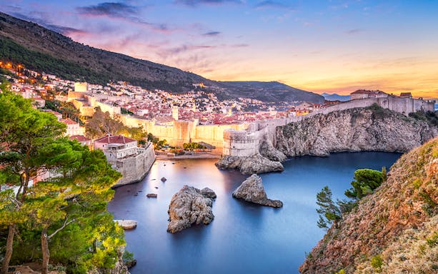 Old town of Dubrovnik at sunset with city walls and Adriatic Sea.