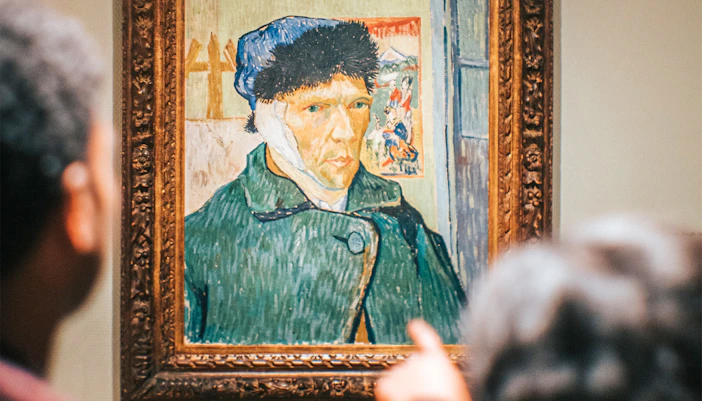 Visitors viewing Van Gogh self-portrait at Van Gogh Museum, Amsterdam.