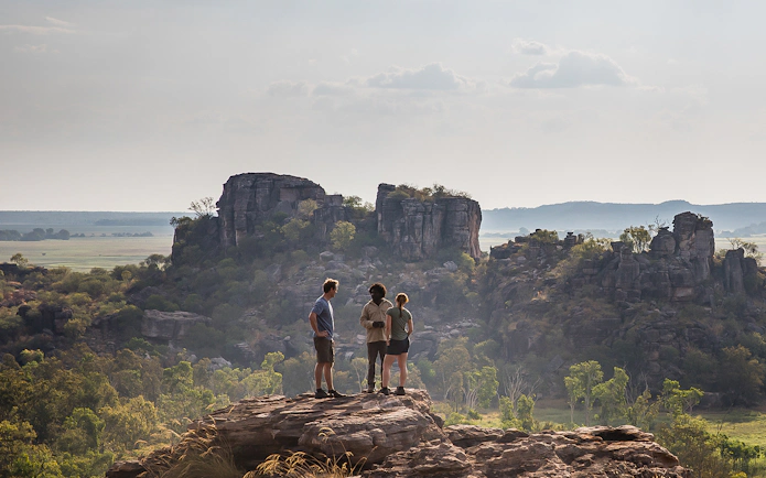 Tourists standing on a rock with views of Kakadu National Park's rocky landscape.