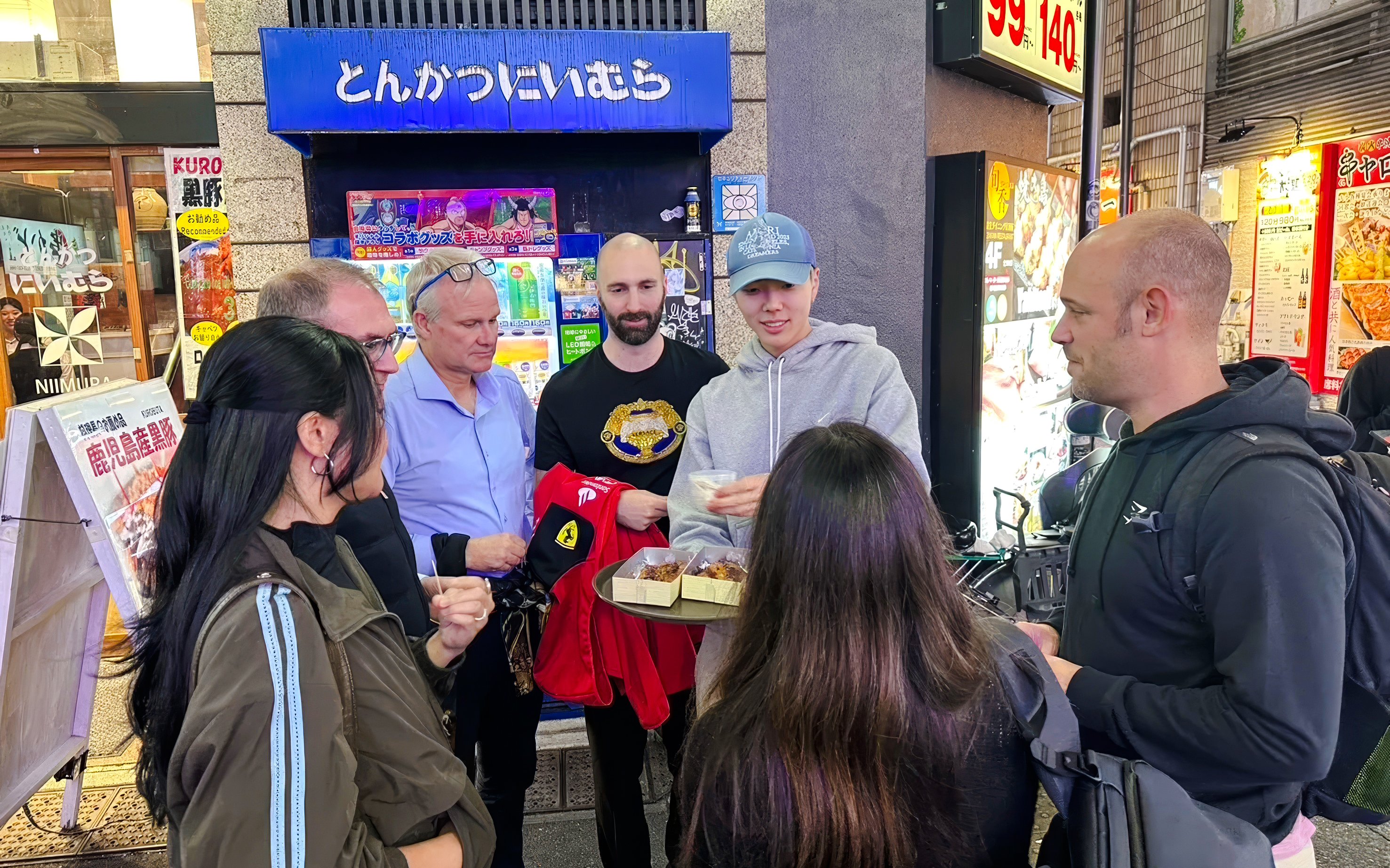 Group enjoying street food on Shinjuku food tour in Tokyo, sampling dishes outside an eatery.
