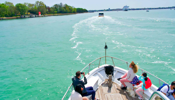 Tourists on a boat enjoying views of Murano, Burano, and Torcello Islands.