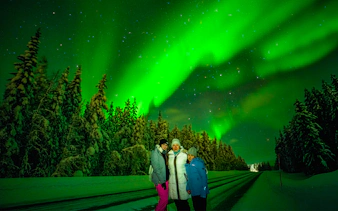 Family enjoying Northern Lights in snowy Rovaniemi forest.