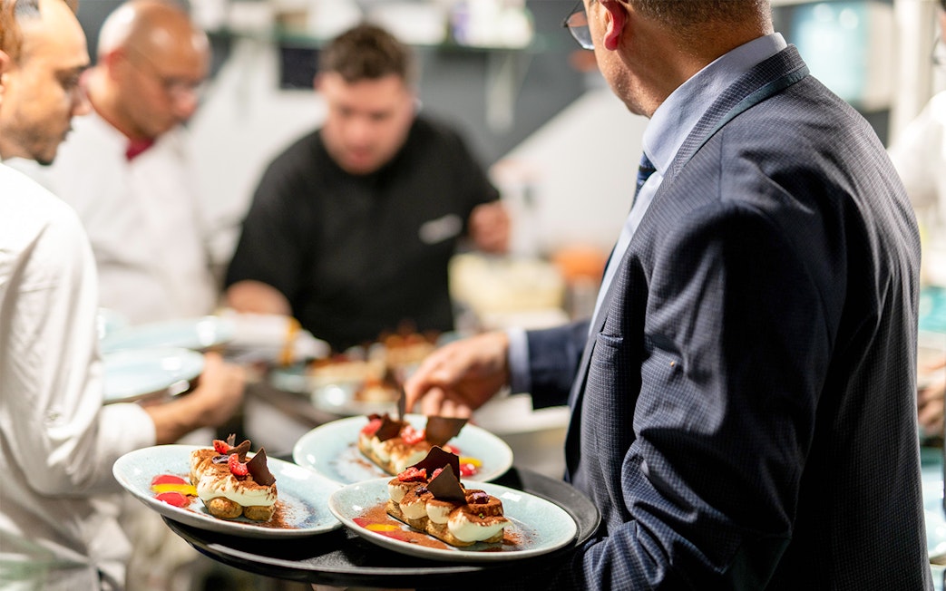 Server presenting dessert plates on THEO Boat Brunch cruise in Paris.