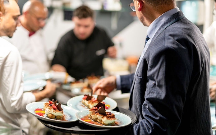 Server presenting dessert plates on THEO Boat Brunch cruise in Paris.