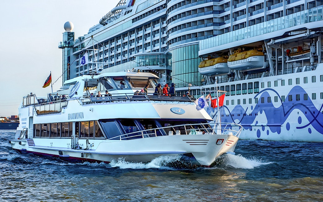 Cruise boat on Hamburg Harbor with Elbphilharmonie in background.