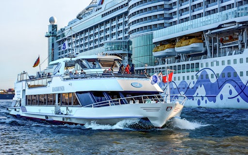 Cruise boat on Hamburg Harbor with Elbphilharmonie in background.