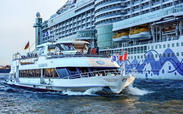 Cruise boat on Hamburg Harbor with Elbphilharmonie in background.