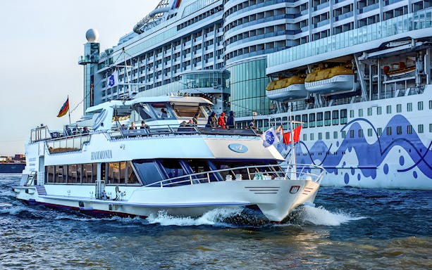 Cruise boat on Hamburg Harbor with Elbphilharmonie in background.